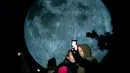 Pengunjung berswafoto dengan latar belakang replika bulan raksasa yang dipajang di Bratislava, Slovakia, 7 Oktober 2017. Replika bulan tersebut merupakan karya seniman Inggris, Luke Jerram yang bertajuk 'Museum of The Moon'. (JOE KLAMAR / AFP PHOTO)