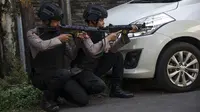 Aparat kepolisian mengambil posisi saat melakukan penjagaan menyusul serangan bom bunuh diri di Polrestabes Surabaya, Senin (14/5). Seluruh akses menuju Mapolrestabes ditutup total dan tiap jalur dijaga polisi bersenjata laras panjang (AFP/JUNI KRISWANTO)
