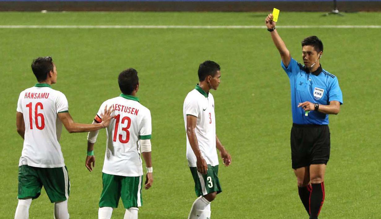 Wasit Kim Heegon dari Korea memberikan kartu kuning kepada pemain Indonesia U-23, M. Abduh Lestaluhu (3) setelah melakukan pelanggaran terhadap pemain Myanmar U-23. (Bola.com/Arief Bagus)