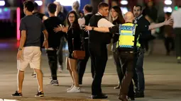 Seorang anggota polisi berusaha menjauhkan orang-orang dari London Bridge, setelah dua serangan teror di pusat kota London, Sabtu (3/6). Serangan brutal terjadi di London Bridge dan Borough Market, yang dilakukan lima orang pria. (AP Photo/ Matt Dunham)