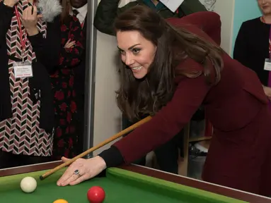 Kate Middleton bersiap memukul bola ketika bermain biliar saat kunjungannya ke MIST, sebuah tempat kesehatan mental bagi anak di Pontypool, Wales, Inggris (22/2). Kate terlihat menikmati permainan biliar tersebut. (AFP Photo / Pool / Paul Edwards)