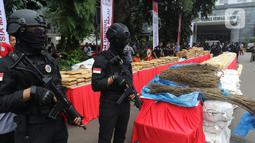 Polisi bersenjata berjaga dekat barang bukti saat rilis pemusnahan narkoba di Mapolda Metro Jaya, Rabu (19/2/2020). Barang bukti tersebut merupakan hasil temuan dijajaran Polres selama bulan Januari 2020 seperti sabu, ganja, esktasi, heroin, happy five dan gorilla. (Liputan6.com/Herman Zakharia)