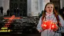 Seorang memegang lilin di depan Katedral Kristus Juruselamat Moskow, Rusia, Senin (12/2). Pesawat Saratov Airlines jatuh setelah lepas landas dari Bandara Domodedovo pada hari Minggu, 11 Februari 2018. (Maxim ZMEYEV / AFP)
