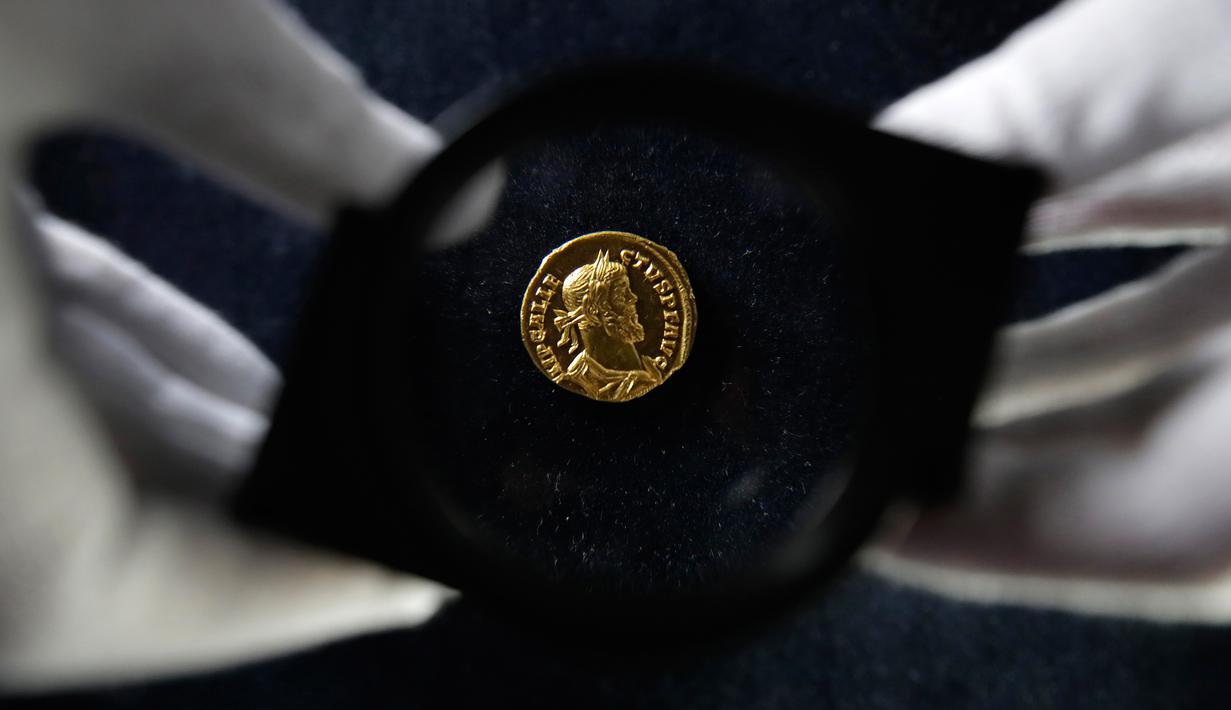 Seorang karyawan Dix Noonan Webb menunjukkan koin Romawi kuno di London, Inggris (28/5/2019). Koin emas ini berasal dari tahun 293-296 M yang ditemukan di sebuah lapangan di Kent, Inggris. (AP Photo/Kirsty Wigglesworth)