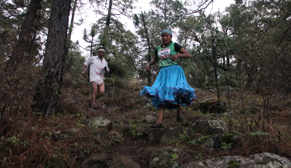 Suku Raramuri dari ras Tarahumara melintasi medan perlombaan lari maraton Ultra Trail Cerro Rojo di negara bagian Chihuahua, Meksiko, Sabtu (15/7). Dalam lomba marathon itu, suku Tarahumara hanya memakai sandal dari karet daur ulang. (Herika MARTINEZ/AFP)