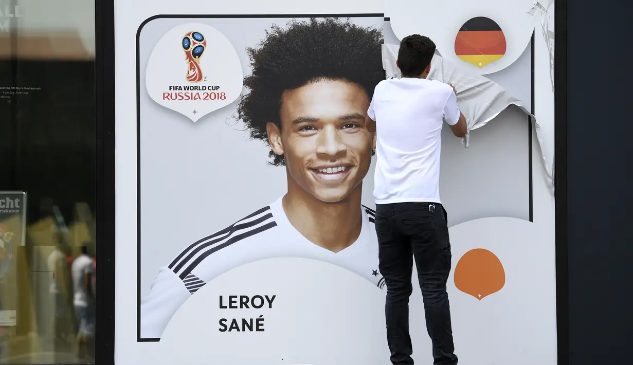 Seorang petugas menurunkan gambar Leroy Sane dari dinding museum sepakbola di Dortmund, (4/6/2018). Pelatih Joachim Low tidak memasukan nama Leroy Sane dalam skuat Der Panzer untuk Piala Dunia 2018. (Federico Gambarini/dpa via AP)