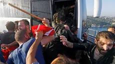 Seorang polisi melindungi tentara dari amukan warga Turki di Jembatan Bosphorus, Istanbul , Turki, (16/7).Tentara berebutan masuk kedalam bus untuk menyelamatkan diri dari pukulan warga. (REUTERS / Murad Sezer)