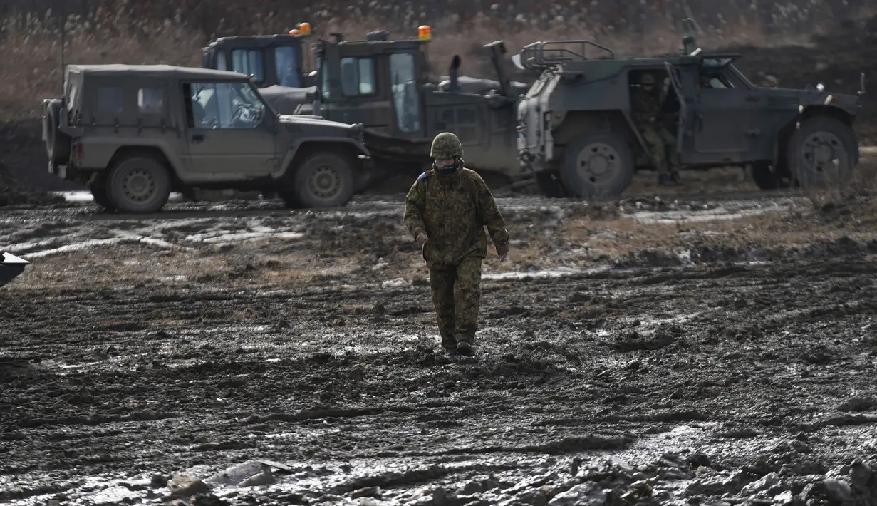 Seorang anggota Pasukan Bela Diri Darat Jepang berjalan di lapangan berlumpur saat latihan tahunan dengan peluru tajam di Minami Eniwa Camp, Eniwa, Pulau Hokkaido, Jepang, 6 Desember 2021. Jepang terus membangun kekuatan militer. (AP Photo/Eugene Hoshiko)