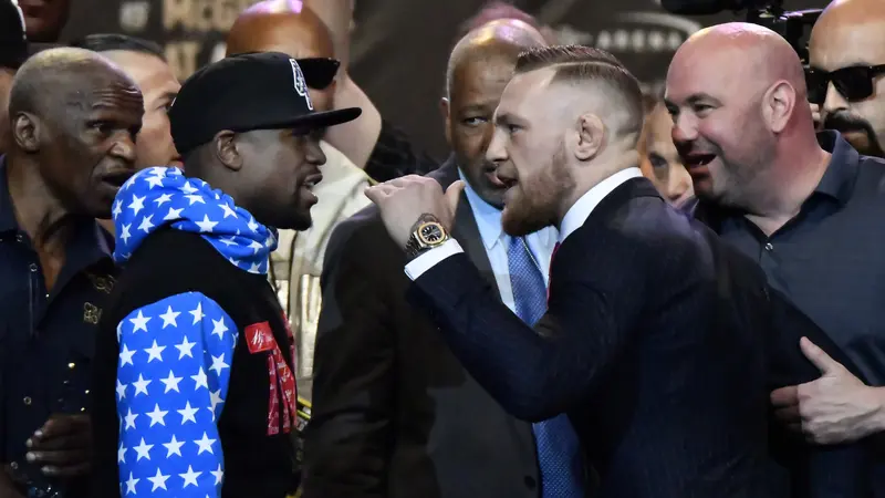 Floyd Mayweather Jr (kiri) adu mulut dengan Conor McGregor pada konferensi pers di Los Angeles, Selasa (11/7/2017). Kedua petarung bakal bertanding di Las Vegas, 26 Agustus mendatang. 