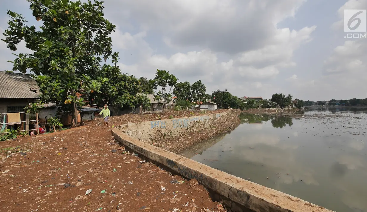 Seorang pria berjalan dekat tumpukan lumpur bercampur sampah dari proyek pengerukan situ Pedongkelan, Cimanggis, Depok, Rabu (28/11). Selain menimbulkan bau, banyaknya lumpur dan sampah membuat lingkungan warga tampak kumuh. (Liputan6.com/Herman Zakharia)