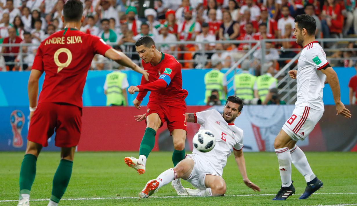Pemain Portugal, Cristiano Ronaldo melepaskan tembakan melewati adangan pemain Iran, Saeid Ezatolahi pada laga grup B Piala Dunia 2018 di Mordovia Arena, Saransk, Rusia, (25/6/2018). Portugal dan Iran bermain imbang 1-1. (AFP/ Jack Guez)
