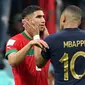 Bek Maroko Achraf Hakimi dihibur oleh penyerang Prancis Kylian Mbappe usai pertandingan semifinal Piala Dunia 2022 di Stadion Al-Bayt di Al Khor, Doha, Kamis (15/12/2022). Maroko gagal melaju ke final Piala Dunia 2022 Qatar setelah kalah dari Prancis dengan skor 2-0. (AFP/Karim Jaafar)