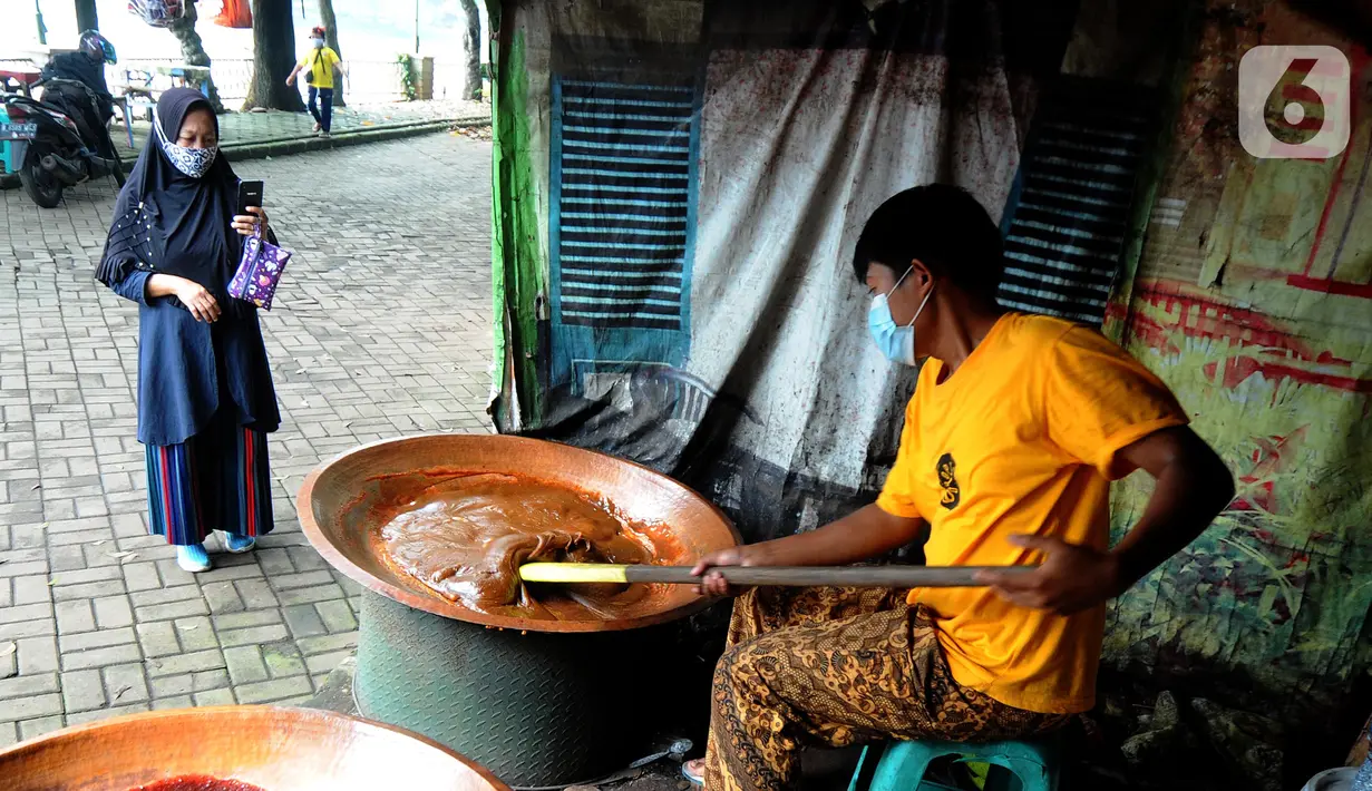 Warga memperhatikan pembuatan dodol Betawi di Setu Babakan, Jagakarsa, Jakarta Selatan, Minggu (4/4/2021). Kios yang boleh dibuka bergantian dengan sistem tanggalan ganjil genap. (merdeka.com/Arie Basuki)