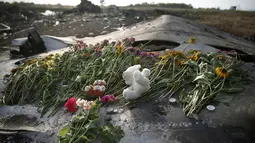 Untaian bunga dan mainan anak diletakkan di salah satu sisa badan pesawat Malaysia Airlines MH-17 yang jatuh dan terbakar di Donetsk, Ukraina, (19/7/2014). (REUTERS/Maxim Zmeyev)
