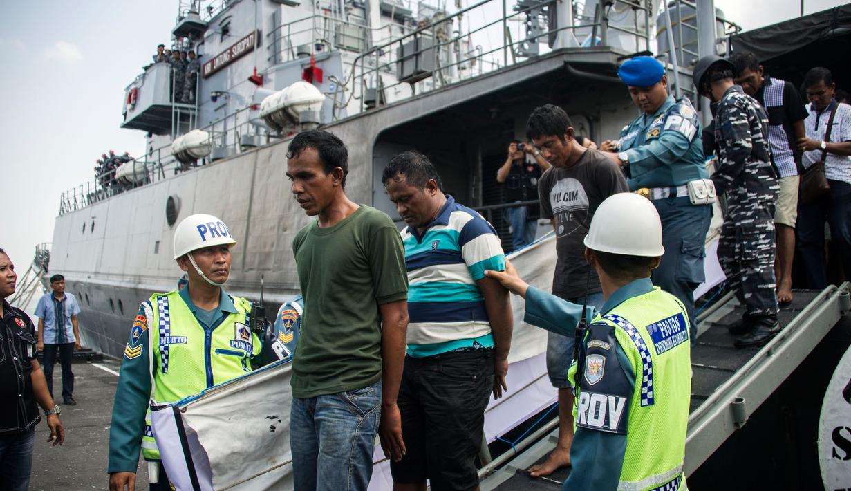 Anggota TNI AL mengawal sembilan tersangka dari sebuah kapal angkatan laut di Surabaya, Jawa Timur, Selasa (10/5). Sembilan tersangka akan dibawa ke Surabaya untuk menjalani pemeriksaan. (AFP PHOTO/JUNI KRISWANTO)