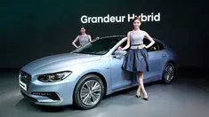 Dua model berpose di dekat mobil Hyundai Motor's Grandeur Hybrid terbaru selama acara Seoul Motor Show di Goyang, Seoul, Korea Selatan, Kamis (30/3). Pameran ini akan diselenggarakan dari 31 Maret hingga April 9. (AP Photo / Lee Jin-man)