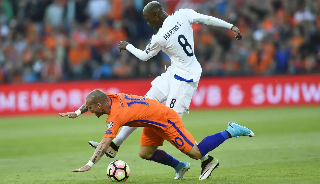 Wesley Sneijder (kiri) terjatuh saat berebut bola dengan pemain Luksemburg, Christophe Martins pada Kualiifikasi Piala Dunia 2018 di Rotterdam. (AFP/ John Thys)