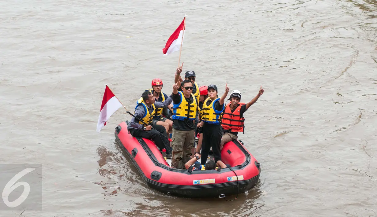 Cagub DKI Agus Harimurti Yudhoyono didampingi istrinya,  Annisa Pohan, mengacungkan jari telunjuk saat menyusuri kali Ciliwung, Jakarta, Rabu (30/11). Agus menyusuri sungai untuk melihat kondisi dan penanganan masalah banjir. (Liputan6.com/Gempur M Surya)
