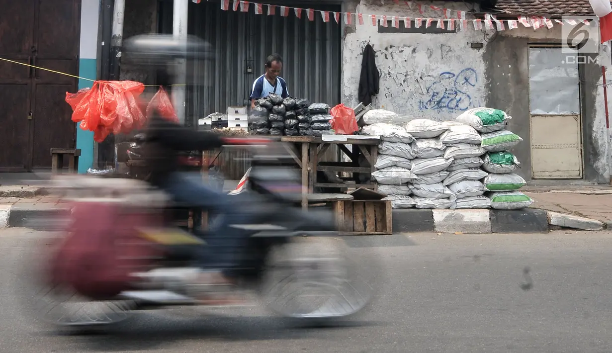Sepeda motor melintas di depan penjual arang, tusuk sate, dan kotak pemanggang di kawasan Manggarai, Jakarta, Rabu (22/8). Belasan penjual perlengkapan membuat sate menjamur saat Hari Raya Idul Adha 2018. (Merdeka.com/Iqbal Nugroho)