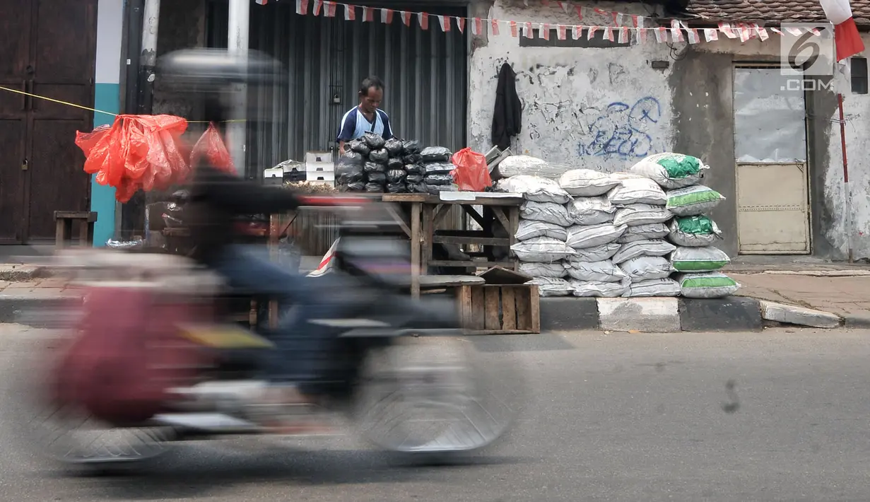 Sepeda motor melintas di depan penjual arang, tusuk sate, dan kotak pemanggang di kawasan Manggarai, Jakarta, Rabu (22/8). Belasan penjual perlengkapan membuat sate menjamur saat Hari Raya Idul Adha 2018. (Merdeka.com/Iqbal Nugroho)