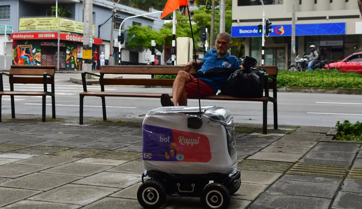 Warga mengamati robot menyusuri jalan di Medellin, Kolombia, Selasa (21/4/2020). Perusahaan rintisan Kolombia, Rappi, menguji coba pengiriman dengan robot sebagai cara aman mendapatkan makanan bagi masyarakat yang terpaksa berada di rumah akibat pandemi virus corona Covid-19. (AP/Luis Benavides)