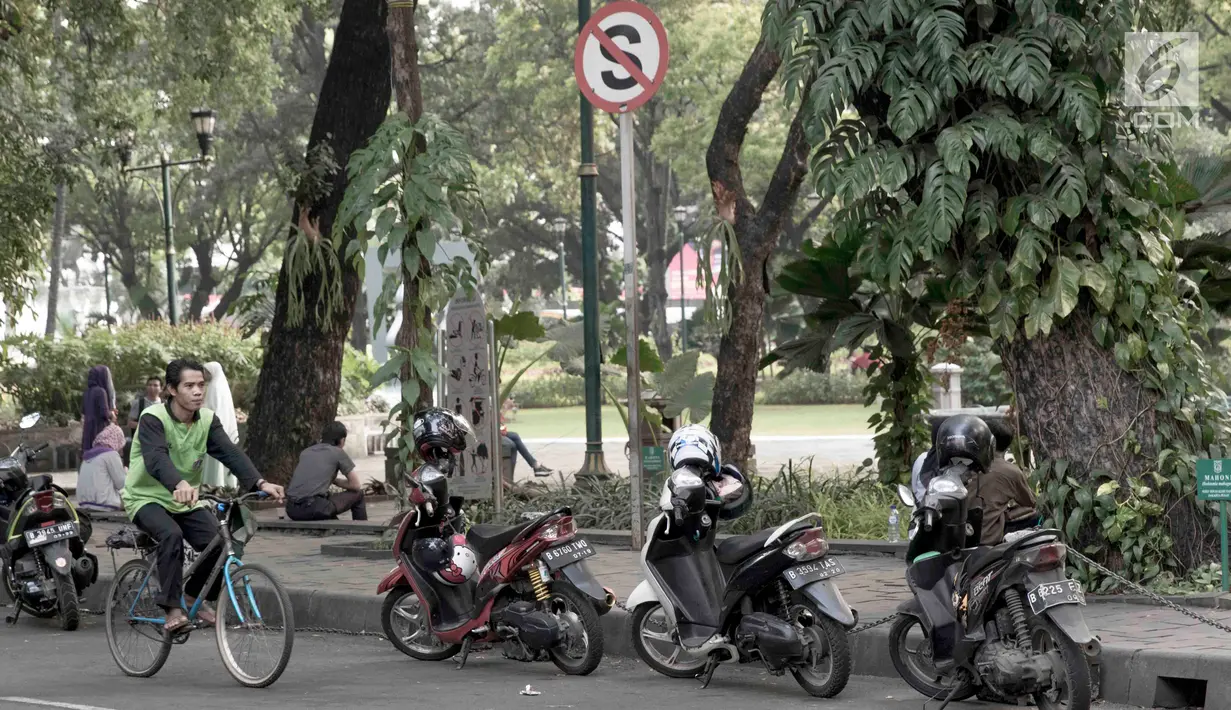 Pengendara sepeda melintas di samping deretan sepeda motor yang terparkir di sekitar Taman Suropati, Jakarta, Selasa (28/8). Meski terpampang rambu larangan parkir dan berhenti, pengendara tetap parkir di sekitar taman. (Liputan6.com/Immanuel Antonius)