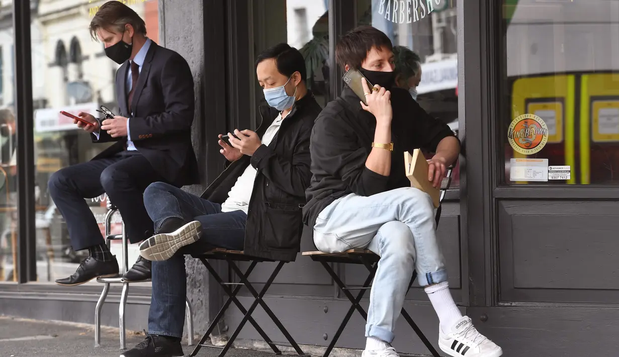Para pria menunggu untuk memotong rambut di luar barber shop di Melbourne, Australia, Senin (19/10/2020). Warga Kota Melbourne, pada Senin (19/10), akhirnya bisa bernafas lega saat sejumlah pembatasan dilonggarkan setelah lockdown tahap keempat yang ketat selama sekitar 100 hari. (William WEST/AFP)