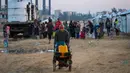 Laporan Perserikatan Bangsa Bangsa (PBB) per Oktober 2025 menyebutkan bahwa sekitar 84% infrastruktur di Gaza, termasuk jaringan air bersih, telah hancur. Pipa-pipa utama rusak parah, menyebabkan jaringan distribusi air lumpuh. Tampak dalam foto, orang-orang mengisi wadah air mereka di kamp Nuseirat untuk pengungsi Palestina di Jalur Gaza tengah pada Kamis 4 Desember 2025. (Eyad Baba/AFP)