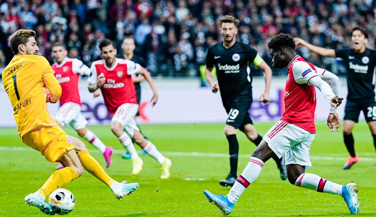 Striker Arsenal, Bukayo Saka, berusaha membobol gawang Eintracht Frankfurt pada laga Europa League di Frankfurt, Kamis (19/9). Frankfurt kalah 0-3 dari Arsenal. (AFP/Uwe Anspach)