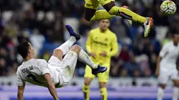 Cristiano Ronaldo melakukan tendangan salto saat dihadang pemain Villarreal, Eric Bally, pada lanjutan La Liga Spanyol di Stadion Santiago Bernabeu, Madrid, Rabu (20/4/2016) atau Kamis dini hari WIB. (AFP/Javier Soriano)