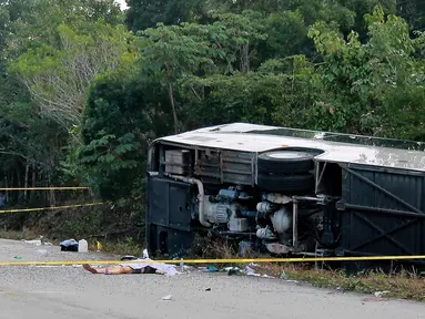 Jasad penumpang tergeletak di dekat bus wisata yang terbalik di jalan raya Mahahual di Quintana Roo, Meksiko, Selasa (19/12). Sedikitnya 12 turis tewas, satu di antaranya anak-anak, dan 18 lainnya mengalami luka-luka. (Novedades de Quintana Roo via AP)