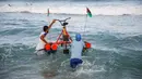 Nelayan Palestina membawa perahu kayuh yang dibuat khusus dari bahan daur ulang ke dalam air di sepanjang pantai di Beit Lahia, Jalur Gaza pada 29 September 2020. (Photo by MOHAMMED ABED / AFP)