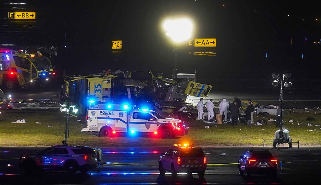 Diinformasikan ada lebih dari 400 penerbangan dibatalkan pada Senin (23/3/2026) pagi waktu setempat. Tampak dalam foto, para petugas memeriksa area di sekitar mobil pemadam kebakaran bandara di landasan pacu Bandara LaGuardia setelah terjadi tabrakan dengan pesawat Air Canada yang baru saja mendarat, Senin 23 Maret 2026, di New York. (AP Photo/Ryan Murphy)