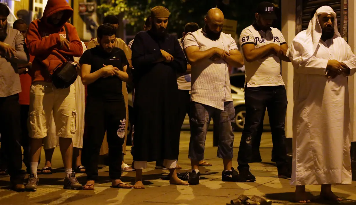 Sejumlah pria muslim salat di lokasi sebuah van yang menabrak pejalan kaki di Finsbury Park Road, London utara, Senin (19/6). Polisi masih terus menyelidiki apakah tabrakan ini murni kecelakaan atau terdapat unsur kesengajaan. (DANIEL LEAL-OLIVAS / AFP)