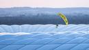 Seorang aktivis Greenpeace dengan menggunakan paraglider saat akan memasuki Stadion Allianz Arena, Muenchen. Belum bisa dipastikan aksi yang bisa dibilang berani tersebut ditujukan kepada pihak siapa. (Foto: AP/DPA/Matthias Balk)