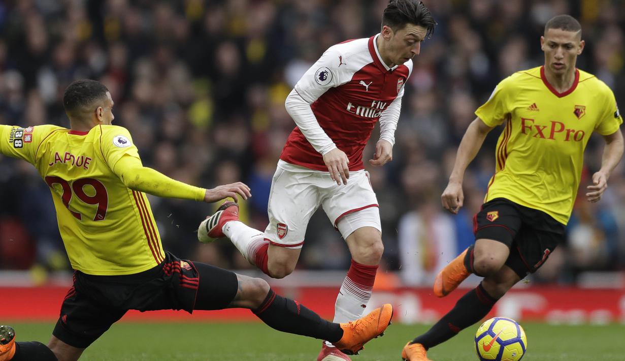 Gelandang Arsenal, Mesut Ozil, berusaha melewati pemain Watford pada laga Preimer League di Stadion Emirates, Minggu (11/3/2018). Arsenal menang 3-0 atas Watford. (AP/Matt Dunham)