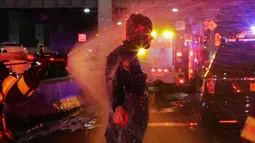 Seorang penyelam FDNY disemprot air setelah mengevakuasi korban jatuhnya helikopter di East River di New York City, AS (11/3). Heli itu sempat terjungkal sebelum akhirnya masuk ke dalam air. (Eduardo Munoz Alvarez/Getty Images North America/AFP)