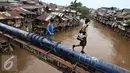 Warga menyebrangi bantaran Kali Ciliwung, Jakarta, Rabu (20/1). Apabila rusun yang disediakan telah siap ditempati Pemprov DKI Jakarta akan melakukan penggusuran pemukiman kumuh sebanyak mungkin. (Liputan6.com/Immanuel Antonius)