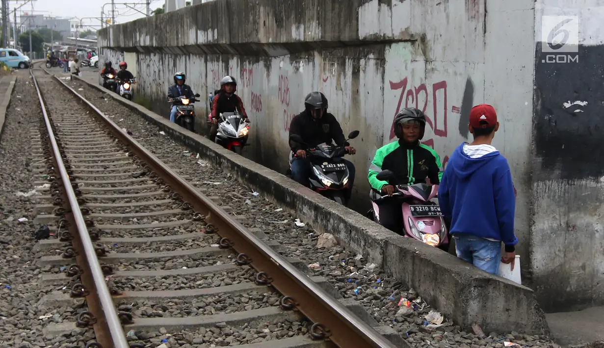 Sejumlah pengendara melintas di samping rel kereta yang berada di kawasan Banjir Kanal Barat, Jakarta, Selasa (20/3). Aksi nekat tersebut membahayakan diri sendiri maupun pengguna jalan lain. (Liputan6.com/Arya Manggala)