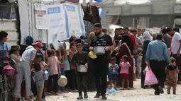 Keluarga-keluarga Palestina yang mengungsi sambil memegang wadah kosong menunggu giliran untuk mengambil makanan dari dapur amal, di kamp pengungsi Bureij, Jalur Gaza Tengah pada Senin 18 Mei 2026. (Eyad Baba/AFP)