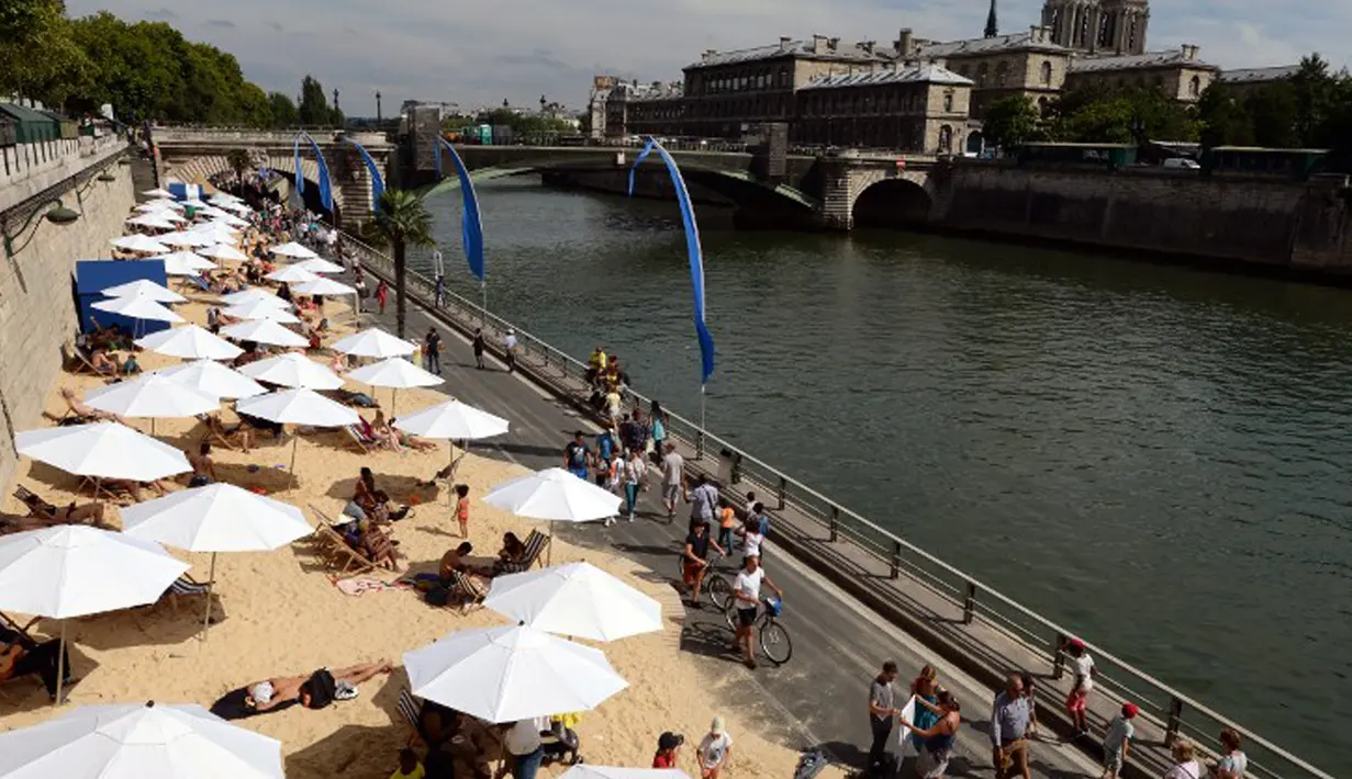 Bantaran Sungai Seine disulap menjadi pantai buatan lengkap dengan pasir dan bangku santai, Perancis, Rabu (22/7/2015).  Tahun ini adalah edisi ke-14 dari Paris Plages, acara budaya dan wisata utama di Paris selama musim panas. (AFP Photo/Miguel Medina)