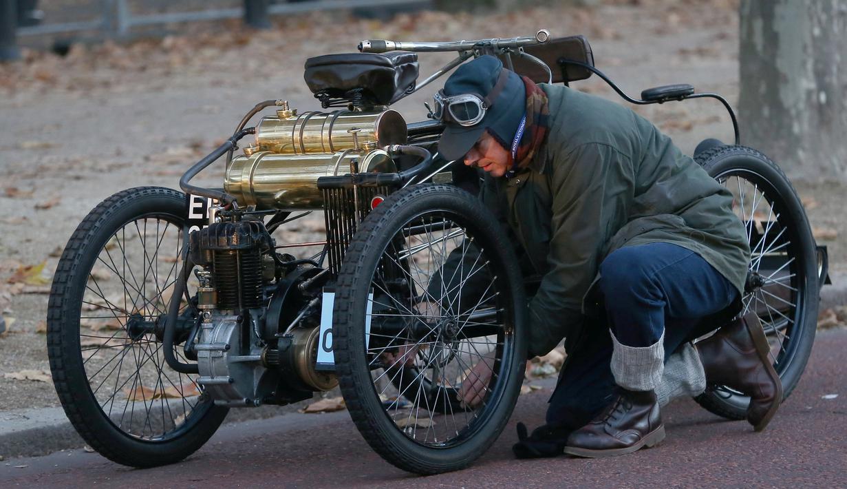 Salah satu peserta memperbaiki mobil klasiknya saat mengikuti kegiatan tur tahunan dengan mobil veteran dari London ke Brighton di London, Inggris (6/11). (Reuters/Neil Balai)