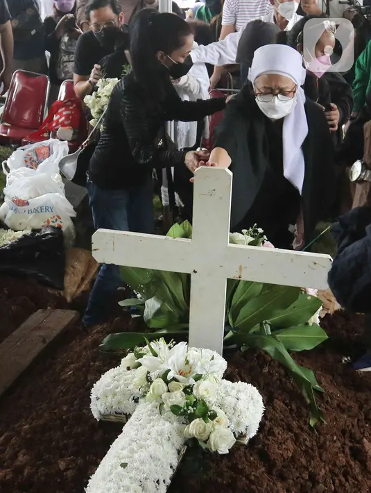 Istri mendiang Bob Tutupoly  Rosmayasuto Nasution  menaruh karangan bunga saat prosesi pemakaman Musisi Legendaris Bob Tutupoly di Tempat Pemakaman Umum (TPU) Tanah Kusir, Jakarta,Kamis (7/7/2022). Sebelum meninggal, diketahui Bob Tutupoly telah dirawat di rumah sakit sekitar satu bulan. (Liputan6.com/Herman Zakharia)