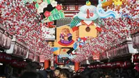 Pejalan kaki melintas di bawah dekorasi shio babi tanah yang mengarah ke kuil Buddha Asakusa Sensoji di Tokyo, Jepang, Kamis (27/12). Tahun 2019 masuk ke dalam shio babi tanah. (AP Photo/Koji Sasahara)