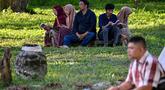 Orang-orang berdoa untuk kerabat mereka yang meninggal dunia dalam peristiwa gempa dan tsunami Aceh pada 2004 lalu di sebuah kuburan massal di Siron, pada 26 Desember 2025. Hari ini, Jumat (26/12/2025), peringatan 21 tahun tragedi gempa dan tsunami Aceh 2004 tetap digelar. (CHAIDEER MAHYUDDIN/AFP)