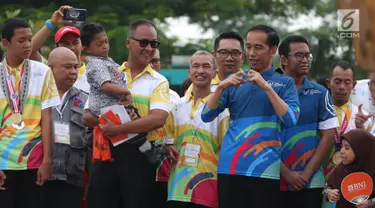 Presiden Joko Widodo menghadiri peringatan Hari Disabilitas Internasional 2018 di Bekasi, Jawa Barat, Senin (3/12). Jokowi bertemu Muklis Abdul Kholik yang sempat viral karena semangatnya untuk bersekolah. (Liputan6 com/Angga Yuniar)