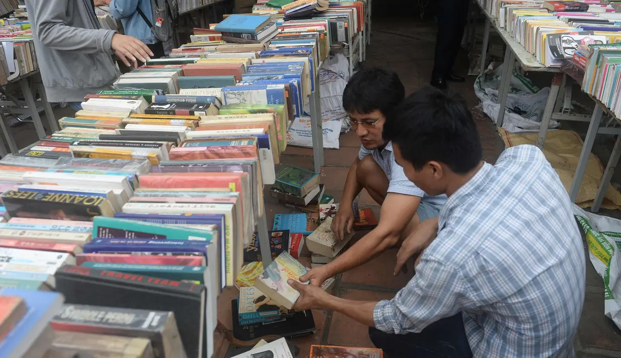 Seorang pria mencari buku selama pameran buku bekas di Hanoi, Vietnam  (26/10).( AFP Photo/Hoang Dinh Nam)