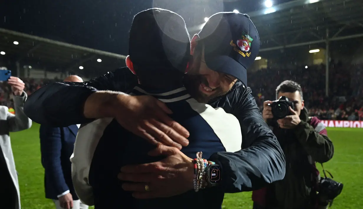 Aktor Hollywood, Ryan Reynolds (kanan) dan pemilik klub Wrexham, Rob McElhenney merayakan kemenangan timnya saat laga English National League antara Wrexham melawan Boreham Wood di Racecourse Ground Stadium, Wrexham, Wales, Sabtu (22/04/2023). Wrexham menang dengan skor 3-1 dan berhasil promosi ke Liga Dua Inggris. (AFP/Oli Scarff)