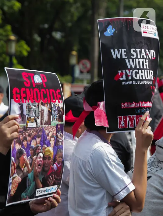 Massa membawa poster bertuliskan 'Stop Genocide' dan 'We Stand With Uyghur' saat menggelar aksi Solidaritas untuk Muslim Uighur di depan Kedutaan Besar China di Jakarta, Jumat (20/12/2019). Mereka mengecam dan mengutuk keras penindasan terhadap muslim Uighur di China. (Liputan6.com/Faizal Fanani)