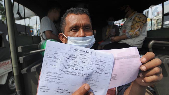 Warga menunjukkan surat bukti pelanggaran saat terjaring dalam razia masker di kawasan Jalan Ir. H. Juanda, Depok, Jawa Barat, Kamis (23/7/2020). Warga yang tidak mengenakan masker dikenai denda Rp 50 ribu hingga Rp 250 ribu. (merdeka.com/Arie Basuki)